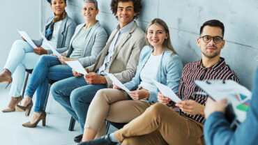 Group of young business people sitting in chairs and waiting for an interview